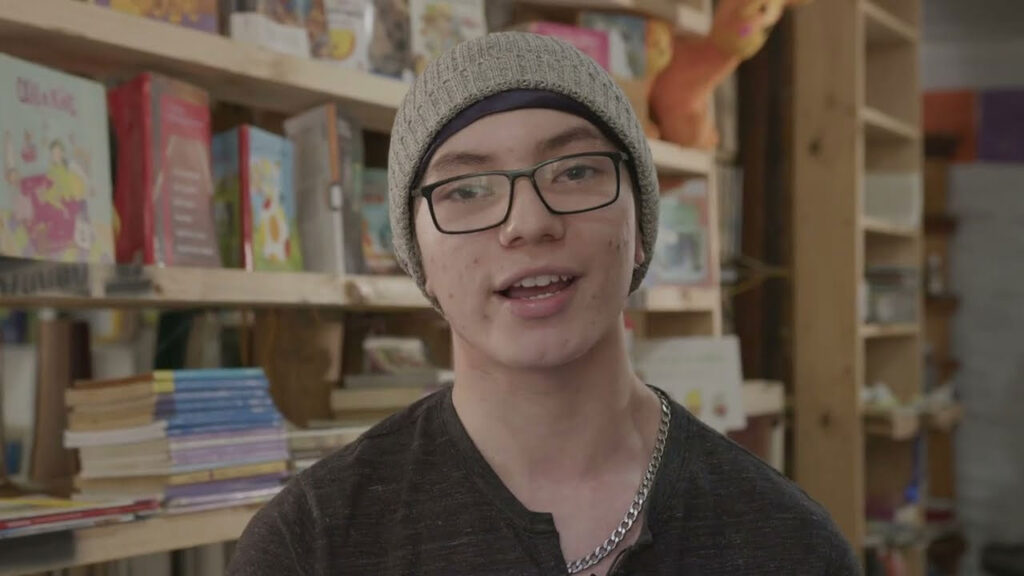 Joven frente a camara hablando en una libreria